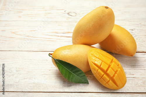Composition with fresh mango fruits on wooden background. Space for text photo