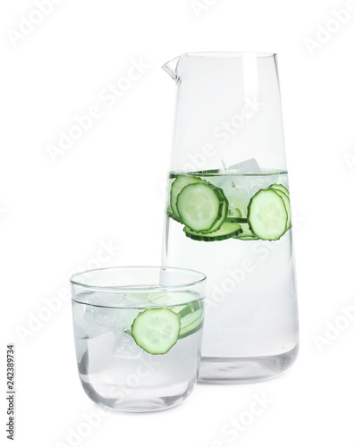 Jug and glass of fresh cucumber water on white background