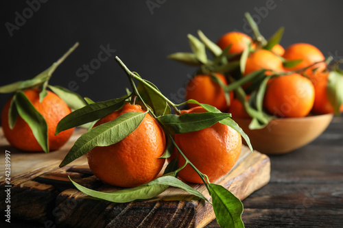 Wooden board with ripe tangerines on table