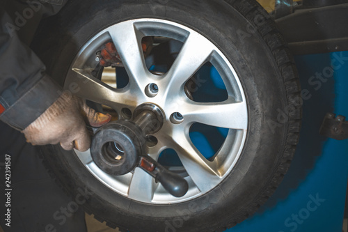 Repairman replaces and balancing car tyre wheel on special balancer equipment tool in car repair service