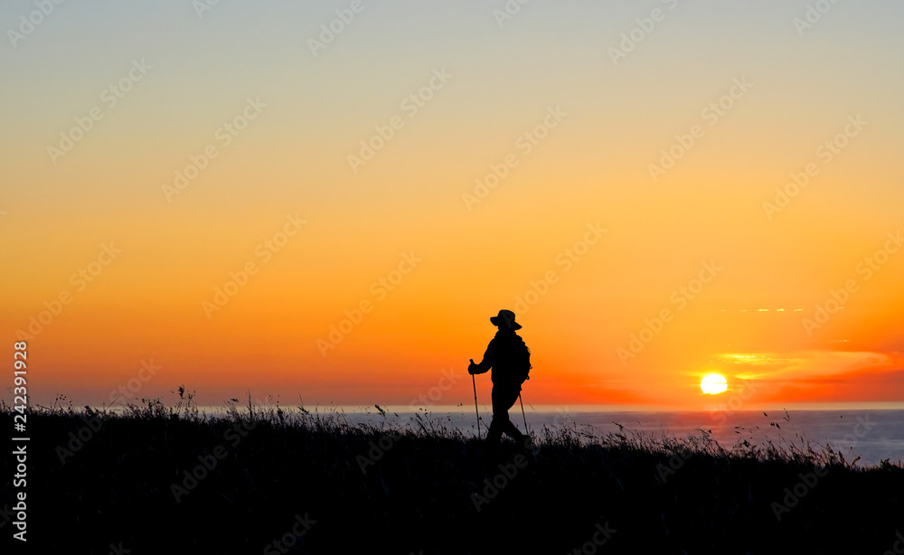 Hiker walking along the Pacific Coast at sunset