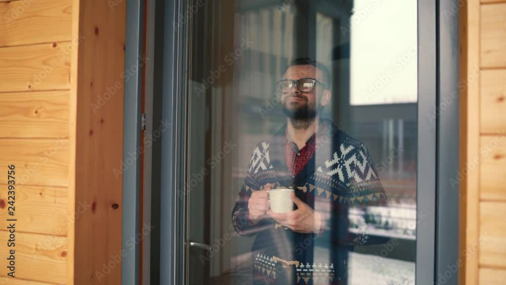 Man drinking tea or coffee near the window and looking through the glass