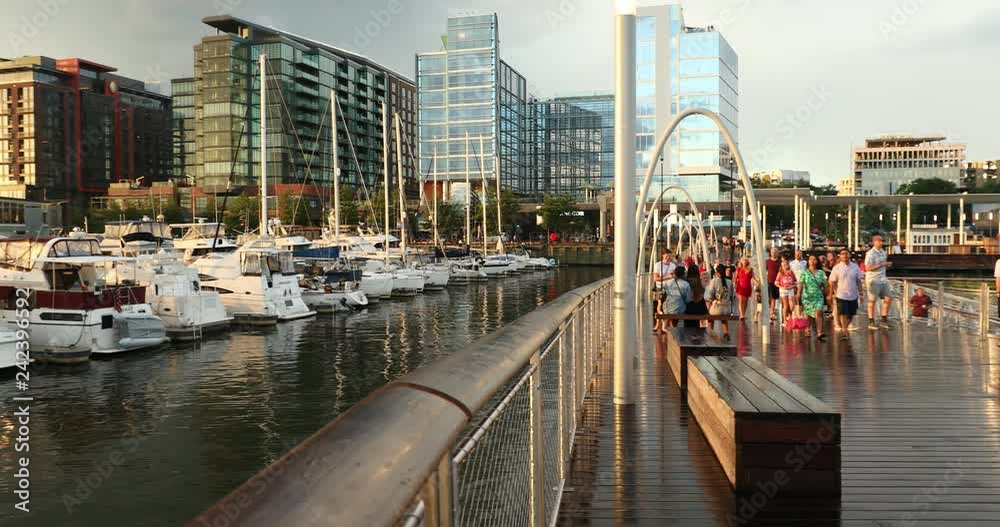 People walk along the marina pier by the hotels and restaurants on the harbour wharf district in Washington DC USA