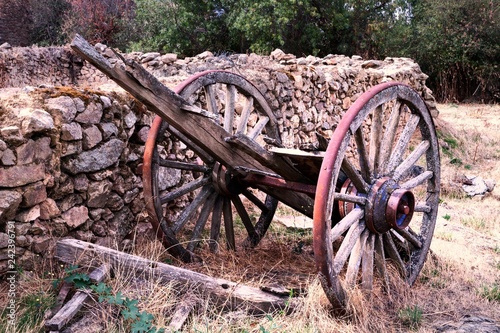 CARRO DE MADERA ANTIGUO ABANDONADO EN CAMPO AL LADO DE MURO DE PIEDRA photo