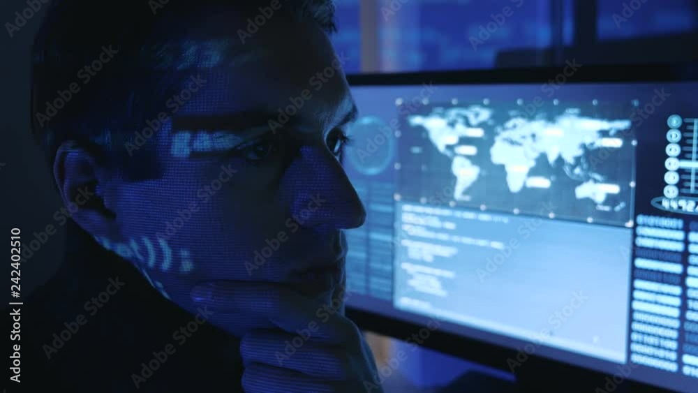 Close-up portrait of a Man Professional Developer Programmer in a data center filled with monitor screens. Hacker works at a computer at night in a dark office. Close-up portrait of a Man Professional Developer Programmer in a data center filled with monitor screens. Hacker works at a computer at night in a dark office.