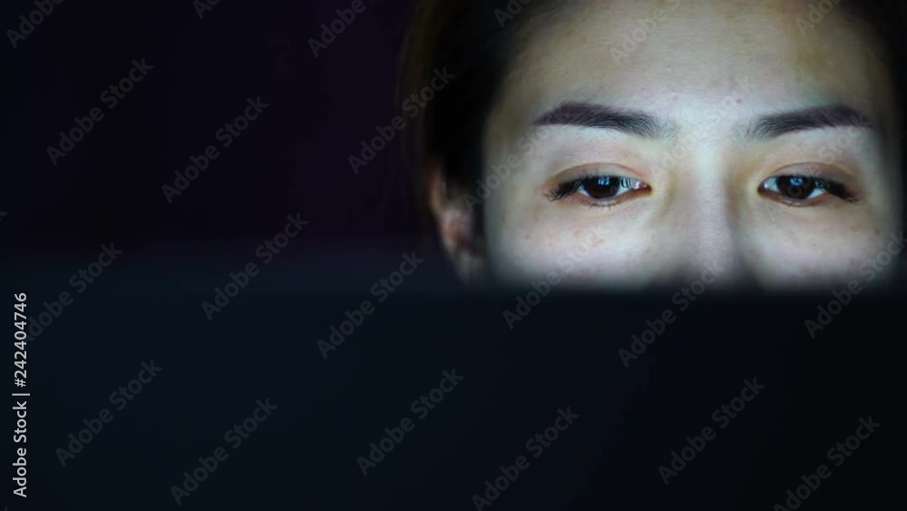 Woman working and look at computer screen at night.