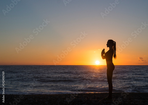 Young healthy woman practicing yoga fitness exercise on the beach at sunset. Healthy lifestyle concept. Copy space text.