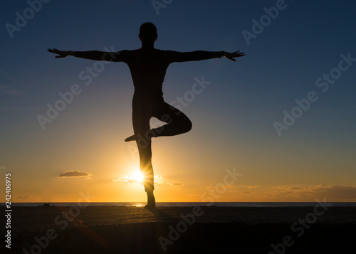 Young healthy woman practicing yoga fitness exercise on the beach at sunset. Healthy lifestyle concept. Copy space text.