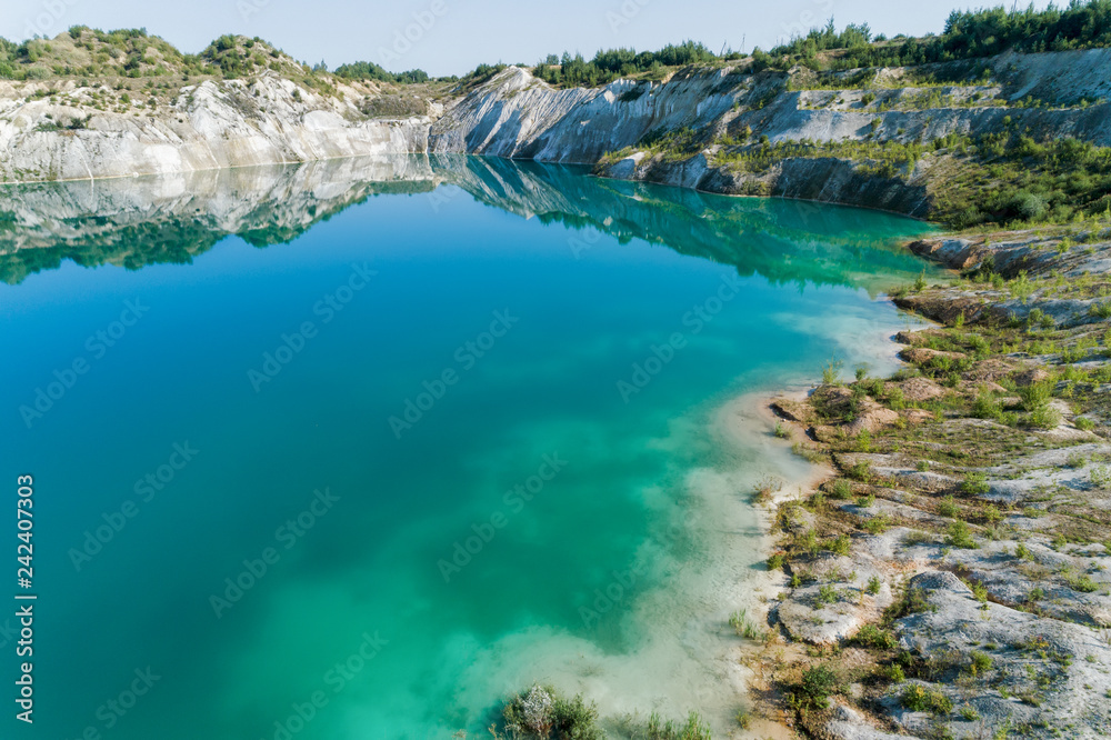An old gypsum quarry filled with blue and pure water. Aerial view, from top to bottom