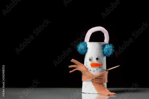 A figure of a snowman made of a toilet paper roll by a child