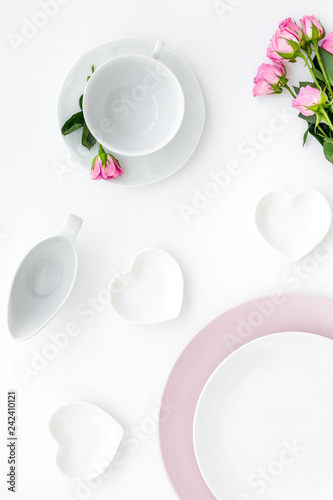 Empty white and pink colorful plate and roses for table setting on white table backgroung top view copy space