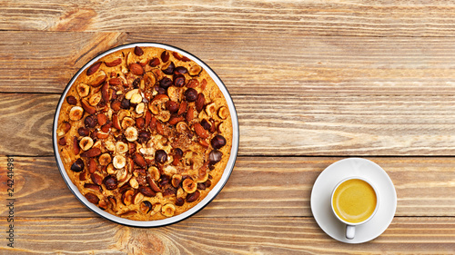 Homemade pie with nuts and cup of coffee on wooden table. Top view. Copyspace.