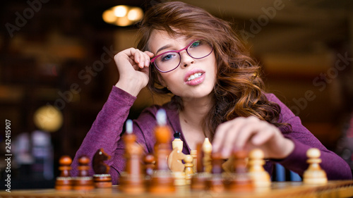 Woman playing chess indoor and thinking position, find winning move, strategy