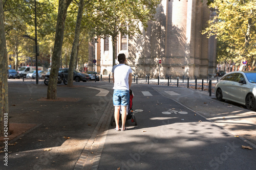 Young man carries a stroller on a  bicycle lane. © AnastazjaSoroka