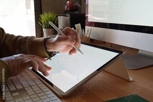 Cropped shot of designer using graphics tablet while working with computer at studio or office photo