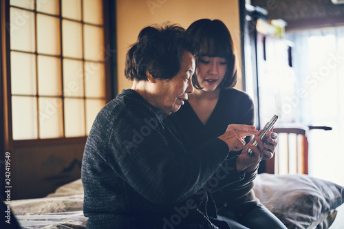 孫にスマートフォンの操作を教わるお婆さん