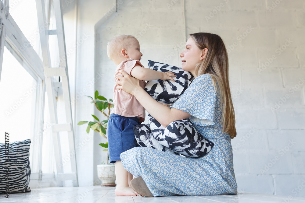 Φωτογραφία Positive beautiful young mother in a blue dress playing with her little funny to