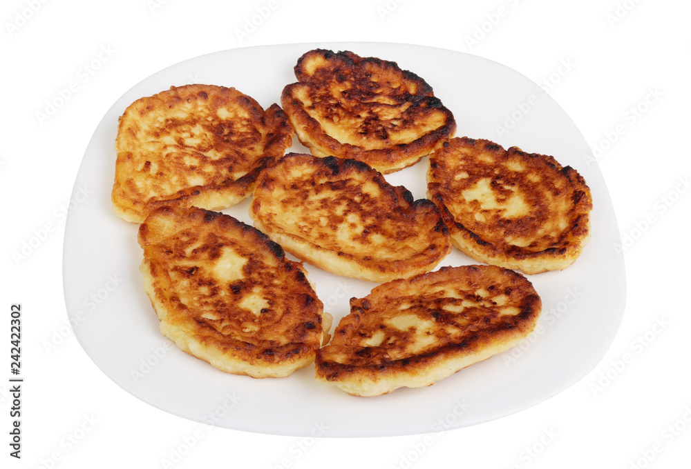Six homemade fried cottage cheese pancakes on a white plate isolated