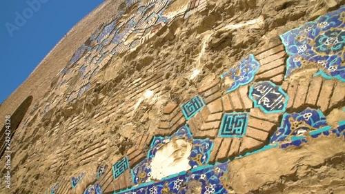 Handheld, medium wide, panning shot of mosaic tiles along wall of the Blue Mosque of Tabriz.