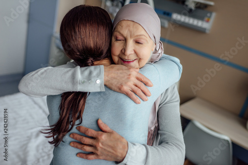 smiling senior woman in kerchief hugging daughter in hospital photo