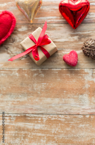 christmas, valentines day and holidays concept - gift box and heart shaped decorations on wooden background