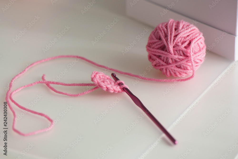 Pink yarn ball with woolen thread on white background