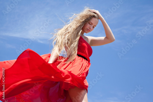Sad teen girl standing against a blue sky