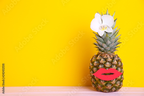 Ripe pineapple with orchid and lips on a yellow background with copy space