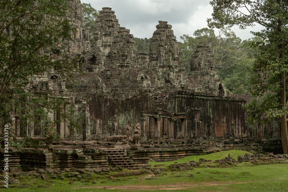 Facade of Bayon temple surrounded by trees