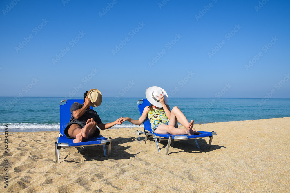 Romantic couple enjoy  in deck chairs on the beach during summer vacations