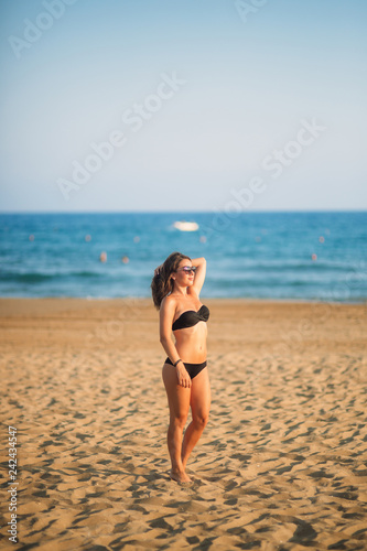 Sexy lady in bikini sunbathing on a sandy beach. Fashion model