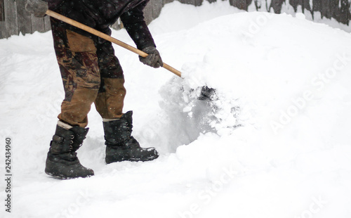 A man cleans snow with a shovel. The dusting of snow. Close up