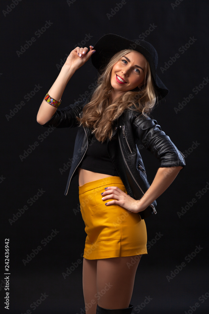 Smiling beautiful young woman in pink mini dress posing with hands on hat. Three quarter length studio shot on turquoise background Smiling beautiful young woman in pink mini dress posing with hands on hat. Three quarter length studio shot on turquoise background