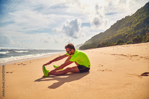 Sportsman stretching on a exotic tropical beach after jogging / exercising. © astrosystem