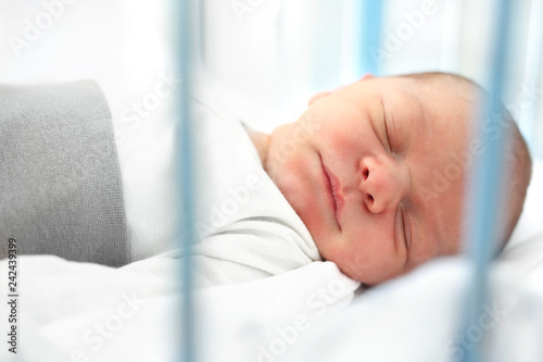 Śpiący noworodek. Pierwsze dni na świecie, noworodek śpi w łóżeczku.