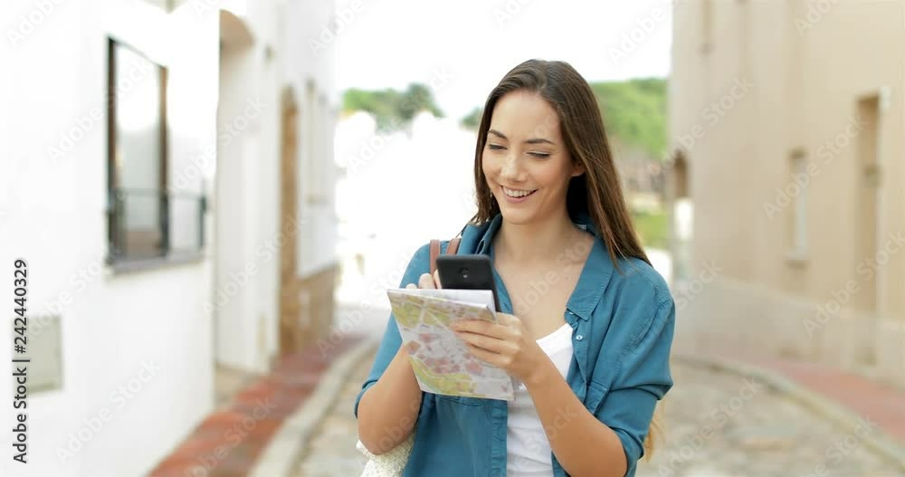 Happy single tourist checking location on smart phone walking in the street on vacation