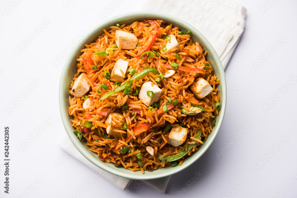 Schezwan paneer fried rice with Szechuan sauce and cottage cheese cubes. served in a bowl or plate or pan. selective focus Schezwan paneer fried rice with Szechuan sauce and cottage cheese cubes. served in a bowl or plate or pan. selective focus