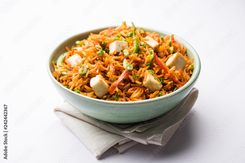 Schezwan paneer fried rice with Szechuan sauce and cottage cheese cubes. served in a bowl or plate or pan. selective focus Schezwan paneer fried rice with Szechuan sauce and cottage cheese cubes. served in a bowl or plate or pan. selective focus