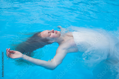Portrait girl in clear water with eyes closed lying on her back