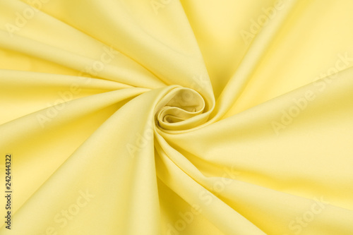 Obraz na płótnie Yellow sateen fabric is laid by folds on diagonal to the center in the form of a