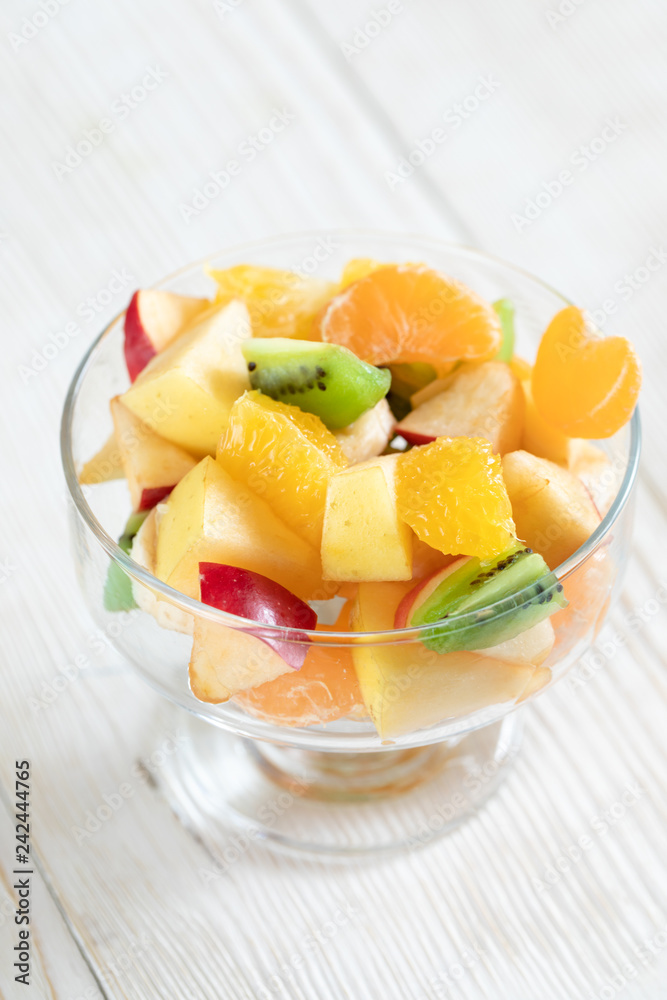 Close-up glass bowl with fruit salad on white wooden table. Close-up glass bowl with fruit salad on white wooden table.