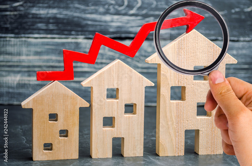 Wooden houses stand in a row from small to large with a red arrow up. concept of high demand for real estate. increase energy efficiency of housing. rise in house prices. property. population growth photo