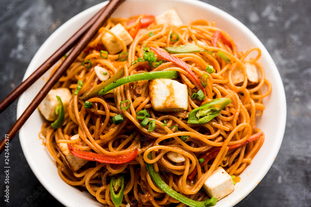 Schezwan hakka noodles with paneer or cottage cheese. Served in a bowl. selective focus