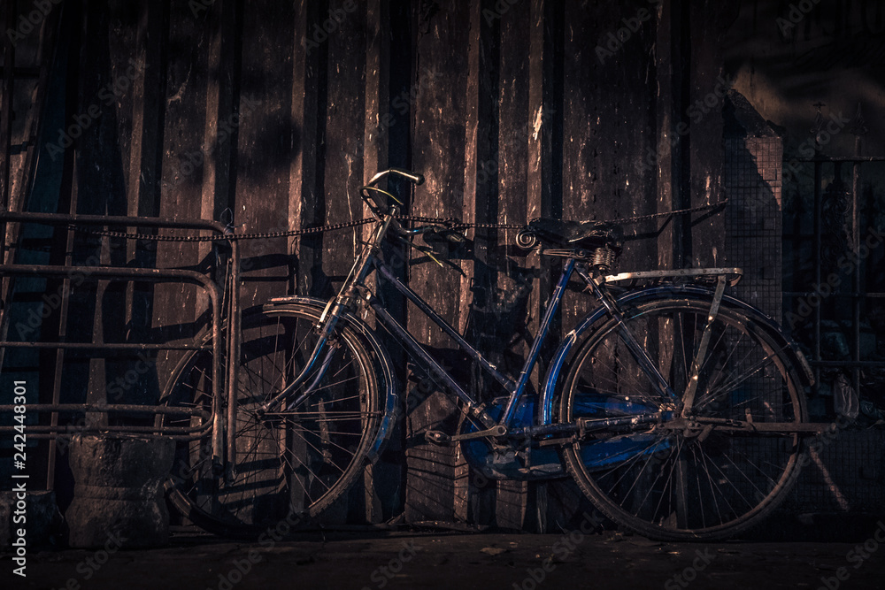 old cycle tied with chain, bicycle standing at dark, old bicycle in blue color
