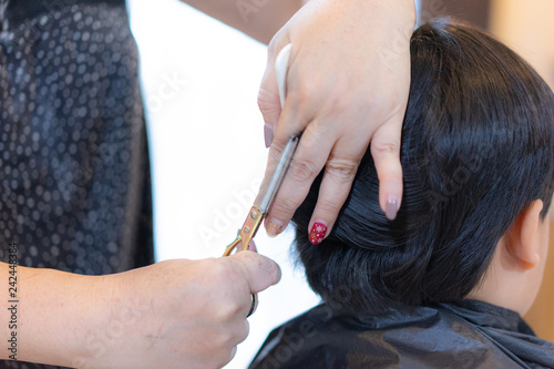 Grandmother is cutting hair of her grandson at home.