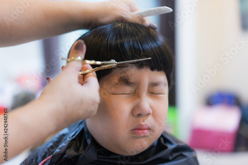 Grandmother is cutting hair of her grandson at home.