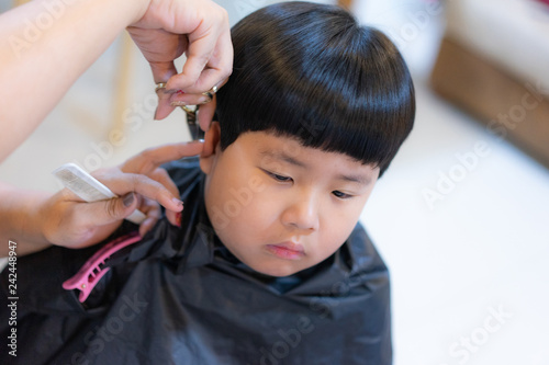 Grandmother is cutting hair of her grandson at home.
