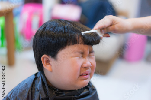 Grandmother is cutting hair of her grandson at home.