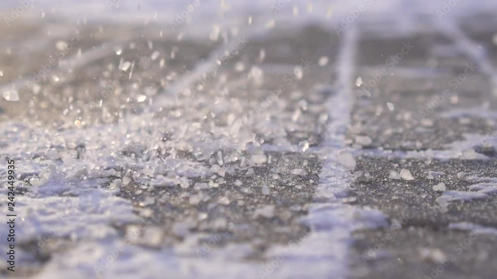 Technical salt reagent is sprinkled on ice in winter close up ,slow mo