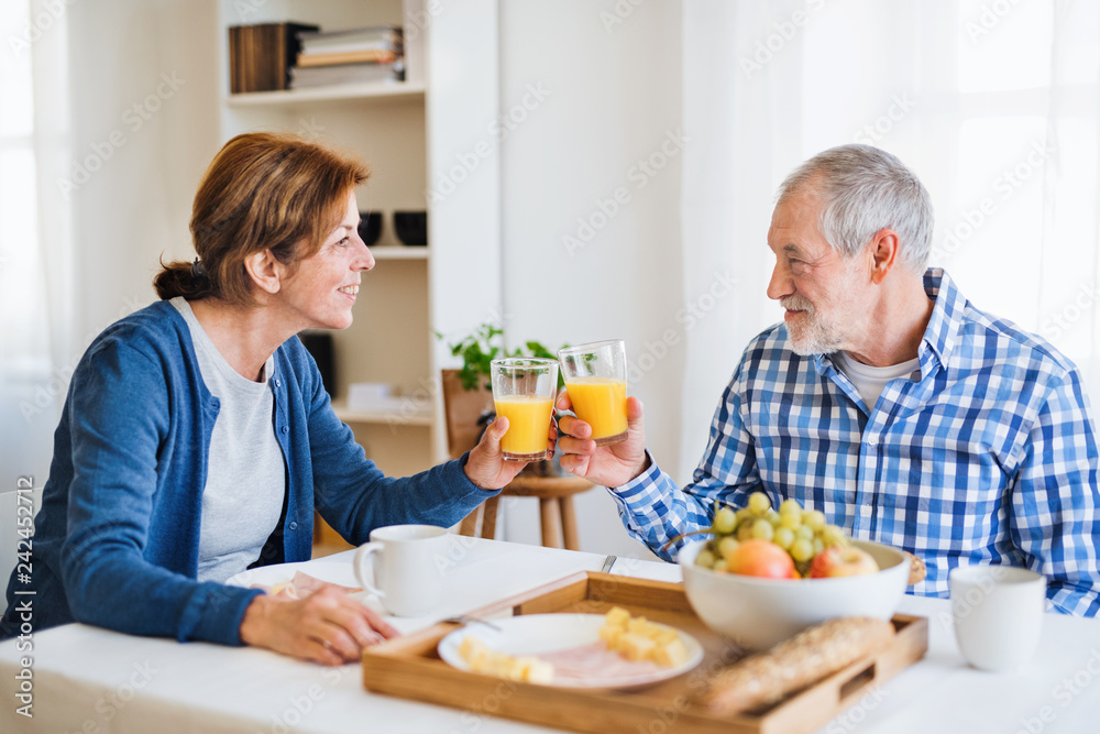 A senior couple sitting at the table at home, having breakfast. A senior couple sitting at the table at home, having breakfast.